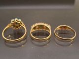 three gold rings with different colored stones on a table