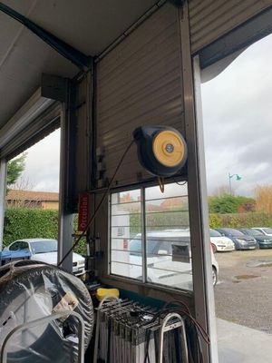 des voitures garées sur un parking à côté d'un immeuble doté d'une grande baie vitrée