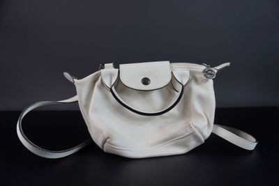 sac à main blanc avec une poignée noire sur un fond noir