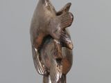 statue of a bird on a marble block with a gray background