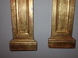 two gold statues on the wall next to each other