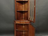 a wooden corner cabinet with a glass door and shelves