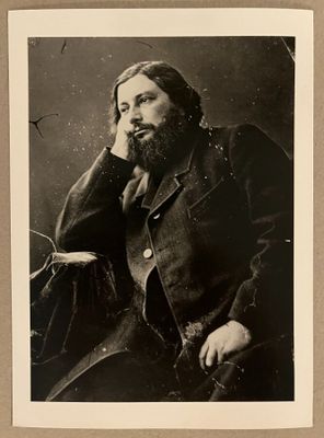photographie en noir et blanc d'un homme barbu assis sur une chaise