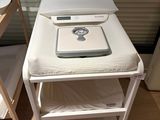 une petite table sur laquelle se trouve une balance, à côté d'un lit