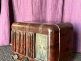 an old radio sitting on the floor next to a purple curtain