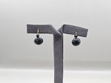 une paire de boucles d'oreilles avec des perles noires sur un support