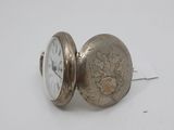 a silver pocket watch sitting on top of a white table