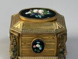 a small gold box with a picture of flowers on it