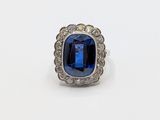 a close up of a blue sapphire and diamond ring on a white surface