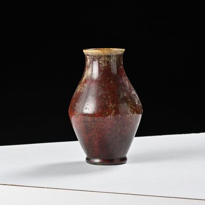 un vase marron posé sur une table blanche