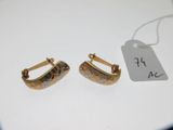 deux paires de boucles d'oreilles en or avec une étiquette de prix posée sur un fond blanc