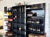 une grande bibliothèque noire sur laquelle sont posées de nombreuses bouteilles