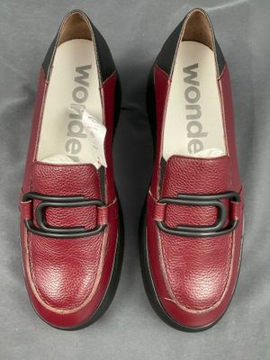 mocassins rouges avec des boucles noires sur une surface grise