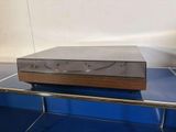 a silver and wood cd player sitting on top of a blue table