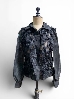 une veste noire ornée de fleurs noires, posée sur un mannequin