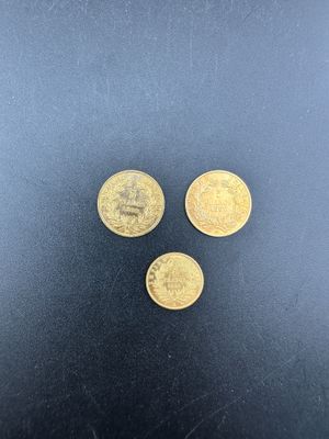 trois pièces d'or posées sur une surface noire