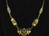 a gold necklace on a mannequin neck with a black background
