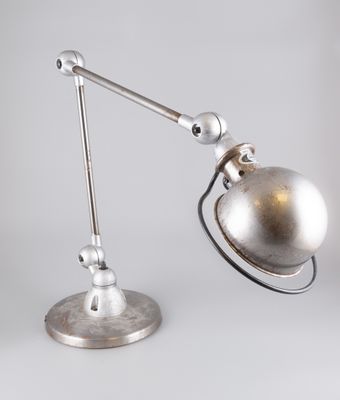 une photo d'une lampe de bureau avec un pied en métal posée sur une surface blanche
