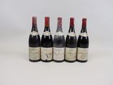 quatre bouteilles de vin sont alignées sur une surface blanche