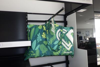 un sac vert et blanc suspendu à une étagère dans un bureau