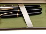 two black and gold fountain pens in a box on a white background