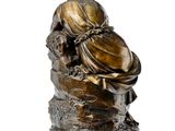 an image of a bronze statue of a woman sitting on a rock