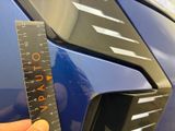 a person holding a ruler to measure the front of a car