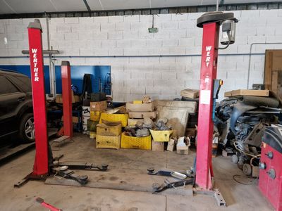 a car that is parked in a garage next to two red lifts