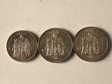 three coins are shown on a white surface, one of which has a picture of a man and a woman on it