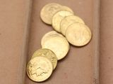 plusieurs pièces d'or posées sur une table marron, à côté d'une paire de ciseaux