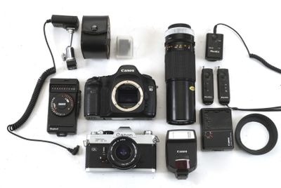 a camera, flash, camera case, flash light, and other electronic equipment laid out on a white surface