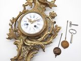une horloge dorée accrochée au mur, à côté d'une clé