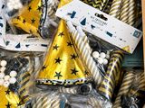 des chapeaux de fête jaunes et noirs et des décorations dans une boîte en carton