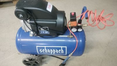 a blue air compressor sitting on the floor in a garage