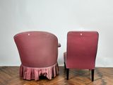 two pink chairs sitting on top of a wooden floor next to a white wall