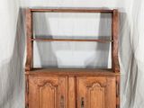 une vieille armoire en bois à deux portes, avec une étagère sur le dessus