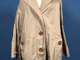 a beige coat on a mannequin stand against a blue background