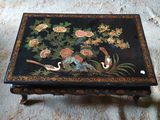 une table noire sur laquelle sont peints des fleurs et des oiseaux