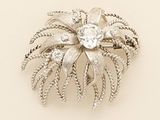 a silver brooch with a flower and leaves on it