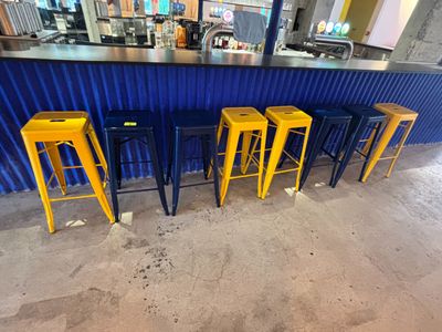 quatre tabourets jaunes posés devant un bar orné d'un rideau bleu