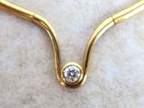 a picture of a gold necklace with a diamond on it