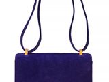 a purple sued purse with a gold handle