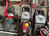 Plusieurs tondeuses à gazon sont alignées dans un garage