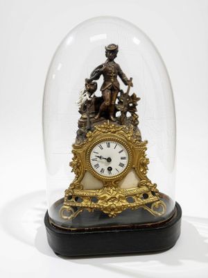 une horloge sous un dôme en verre, surmontée d'une statue