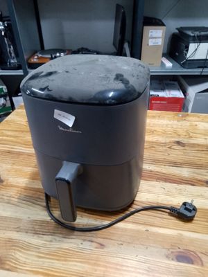 une friteuse à air chaud noire posée sur une table en bois