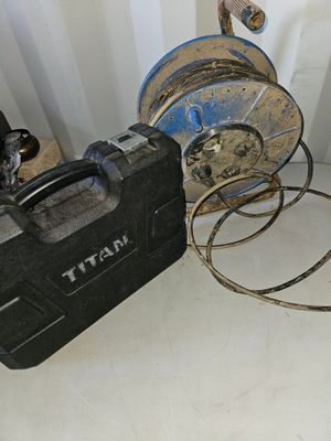 une mallette à outils noire posée par terre à côté de quelques tuyaux