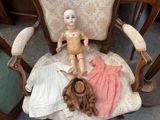 a doll that is sitting on a chair next to a teddy bear