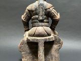 statue of a man sitting on a stool with a helmet on