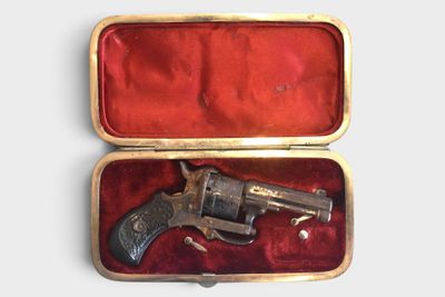 a small gun in a case on a white surface
