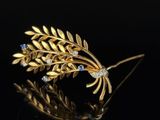 a close up of a gold leaf brooch with blue stones